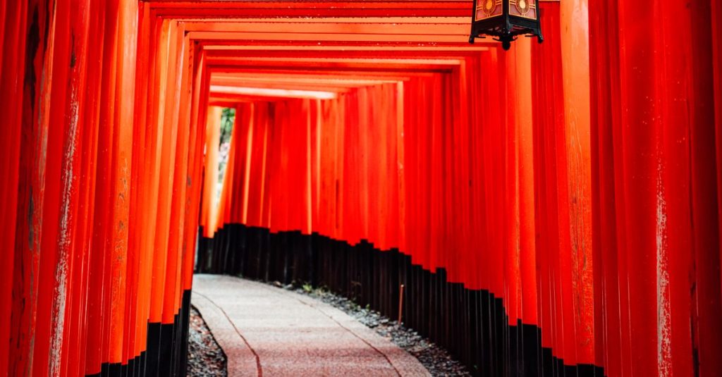 Allée de portiques torii vermillon, avec une lanterne suspendue, au sanctuaire Fushimi Inari